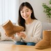 「ムートンブーツが大きい時の対処をイメージした、日本人女性がムートンブーツを手に持ちフィット感を確認しているシーン。明るく清潔感のある室内で撮影され、ブーツのサイズ調整を検討する様子が自然に伝わる構図。